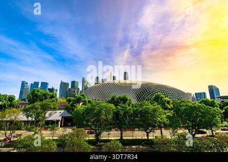 Esplanade Theatres on the Bay modern architectural landmark dome framed by green trees against a vibrant sky backdrop, Singapore cityscape. Stock Photo