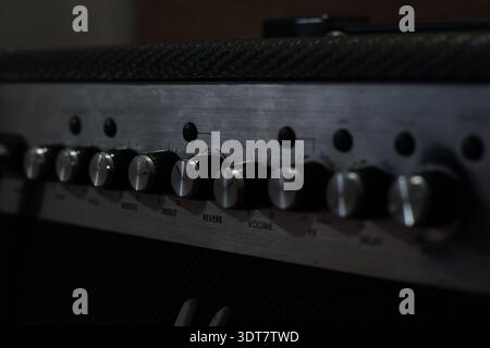This photo presents a close-up view of a guitar amplifier control panel with a sleek, metallic finish. A row of textured knobs lines the front, label Stock Photo