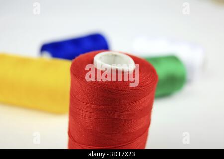 Red spool of thread in focus with other colorful rolls in the background Stock Photo