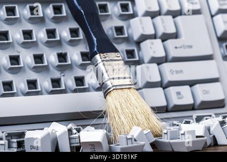 Brush on the old broken computer keyboard. Cleaning old keyboard Stock Photo