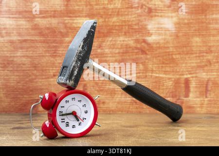 Hammer breaking classic alarm clock . Smashing the time in monday.Business stress, deadline. Dissatisfaction with work. Bad time management Stock Photo