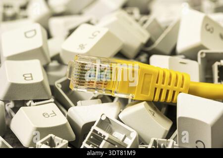 LAN network connection ethernet cable in the pile of keyboard keys. Internet cable RJ45 and keyboard keys close-up view Stock Photo