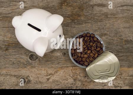 Piggy bank next to opened tin-can full of roasted coffee beans. Coffee market concept Stock Photo