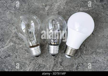 Three different types of light bulbs on grey stone background. Tungsten, halogen and LED light bulbs Stock Photo