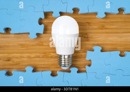 Blue puzzle frame with a bright light bulb in the middle. Concept for problem solving, solution strategy and idea Stock Photo