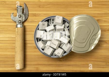 Hungry for information: can opener and tin can full of computer keyboard keys Stock Photo