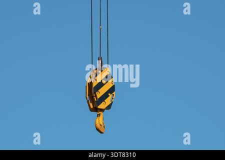 Large yellow crane hook on lifting gears for lifting loads on a background of blue sky. Construction concept Stock Photo