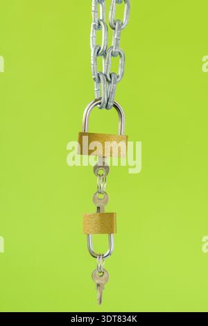 Gold padlocks with keys hanging on the metal chain Stock Photo