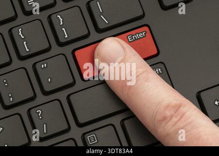 Finger pressing the ENTER button of computer keyboard Stock Photo