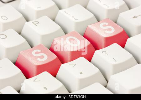 White computer keyboard with red keys arranged in the word SOS. Computer keyboard with SOS keys Stock Photo