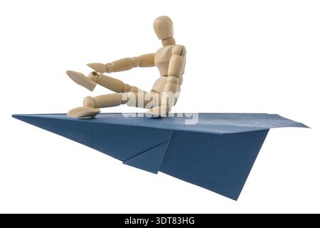 Wooden doll flying on a blue paper plane. Isolated on white background Stock Photo