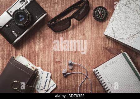 Go on an adventure! The map, old camera, wallet, compass, sunglasses and notebook on a wooden table. Top view Stock Photo