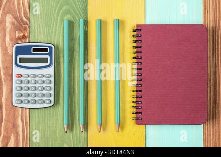 Notebook, calculator and four pencils on colored background Stock Photo