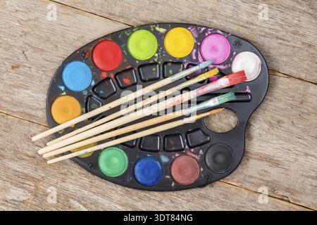 Watercolor paints and brush on wooden background. Top view Stock Photo