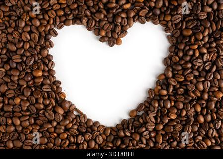 Solid layer of roasted coffee beans featuring a heart shaped hole in the center for custom messages or creative cafe marketing. Stock Photo