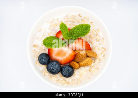 Top Down View of Healthy Oatmeal Breakfast Bowl with Blueberries, Strawberries, Almonds, and Mint on White Background. High quality photo Stock Photo