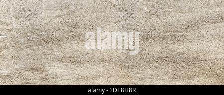 Rough beige plaster wall creating a grainy texture and layered background Stock Photo