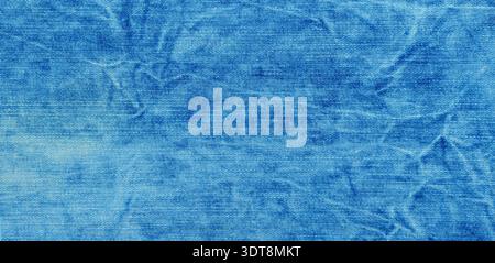 Blue wrinkled denim fabric displaying a faded and worn textile surface Stock Photo