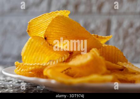 Crispy ridged potato chips on white plate close food texture Stock Photo