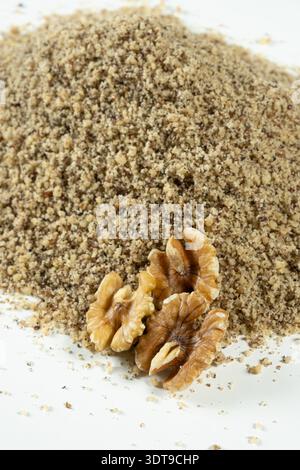 Whole walnut halves on crushed walnut kernels on white background Stock Photo