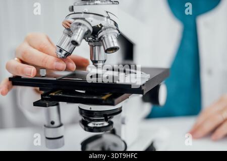 Laboratory specialist examining samples under microscope within biosecurity and global health preparedness framework focusing on pathogen detection Stock Photo