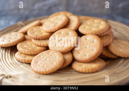 Round salted crackers stacked on wooden serving board close view Stock Photo