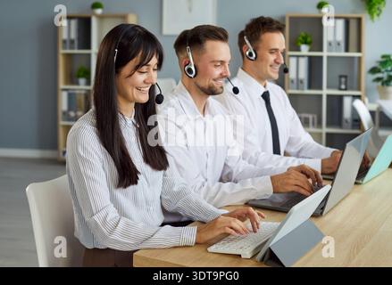 Female and male customer service team with headset devices working at laptops Stock Photo