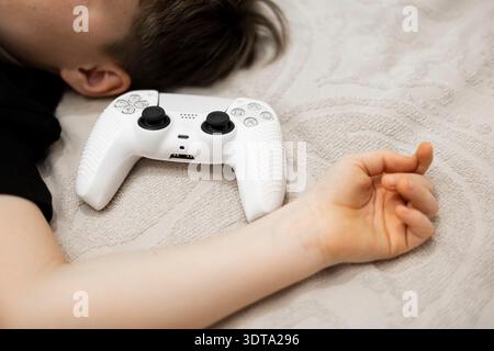 A child and a game controllers pad and playing a video game. Stock Photo