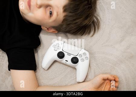 A child and a game controllers pad and playing a video game. Stock Photo