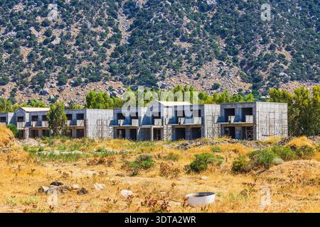 View of unfinished concrete houses on background of mountain landscape. Kos. Greece. Stock Photo