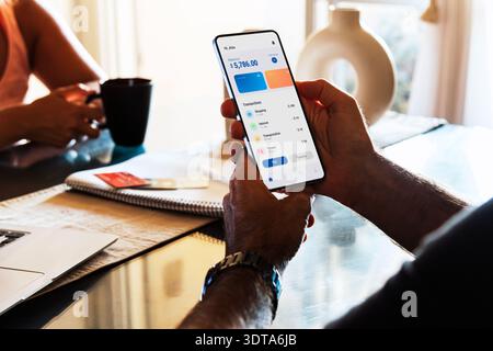 Man at home checking the financial app on his mobile phone. Digital wallet, home finances concepts. Stock Photo