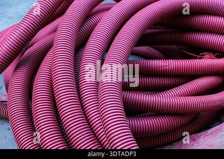 Close-up view of coiled pink corrugated hose highlighting repeating ridged texture and flowing curves; an abstract industrial composition emphasizing Stock Photo