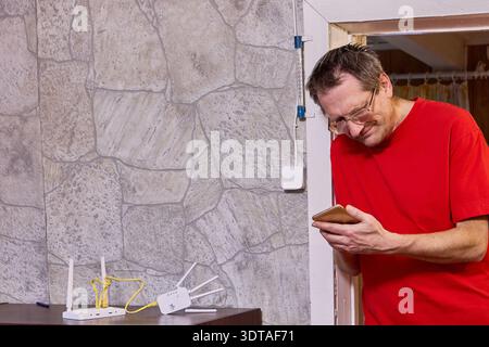 Issue with setting up wifi distribution equipment elderly man uses smartphone to find solution on internet. Stock Photo