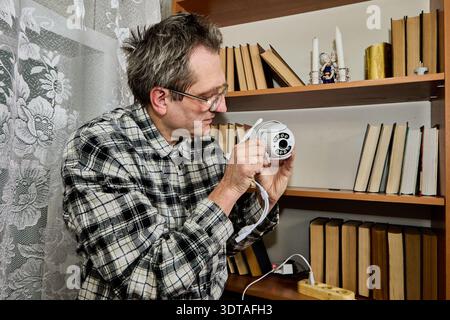 Independent installation of new surveillance camera indoors, farmer conducts tests checking settings. Stock Photo