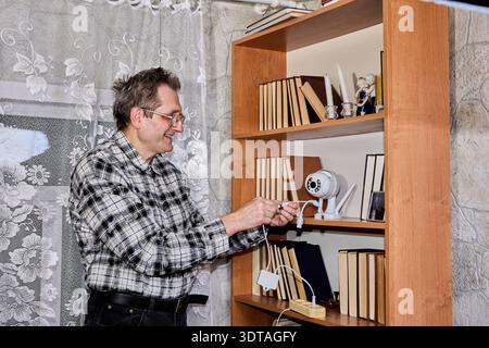 Elderly farmer tests new surveillance camera. Stock Photo