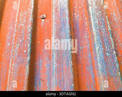 A detailed commercial macro view of a rusted and weathered metal fence with vibrant orange and blue flaking paint layers showing high quality industri Stock Photo