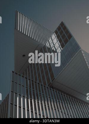 Amsterdam, Netherlands - October 26 2024: Modern abstract geometric high-rise building facade with glass and metal elements against a clear sky. Stock Photo