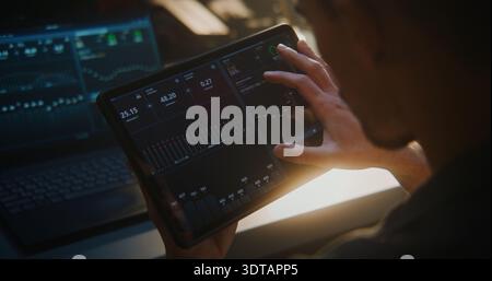 Auto Technician Using Tablet For Engine Diagnostics in Workshop. With Laptop Connected Vehicle, Man Monitors Performance Charts and System Data. Digital Automotive Service and High Tech Maintenance. Stock Photo
