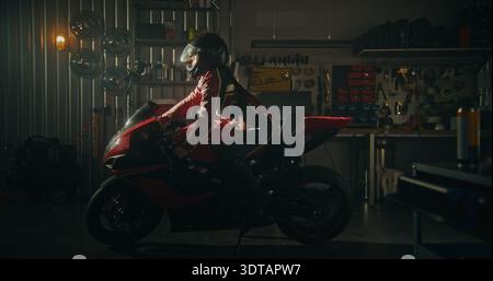 Focused and Determined Asian Woman in Professional Leather Riding Suit Prepares For High Speed Ride Inside Modern Workshop. Female Carefully Puts on Helmet and Pulls on Sleek Black Leather Gloves. Stock Photo