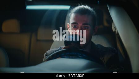 Inside Parked Car, Concentrated Male Driver Studies Phone Screen, Slowly Composing Responses in Serious Exchange. Man Focused Personal or Professional Discussion Unfolding Through Digital Messaging. Stock Photo