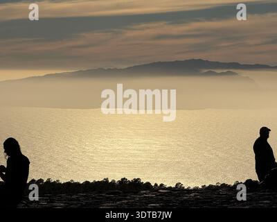 Silhouettes of people watching sunset over Atlantic Ocean and La Gomera from Teide crater, Tenerife Stock Photo