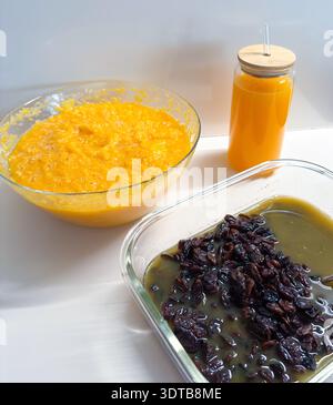 Preparing healthy breakfast with orange puree, juice, and soaked raisins Stock Photo