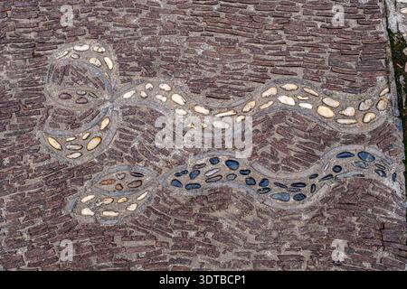 a cobblestone pavement featuring an intricate, symmetrical pattern with alternating dark and light stones forming a geometric design. Stock Photo