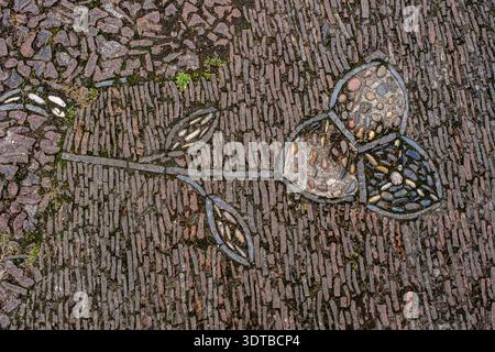 a cobblestone pavement featuring an intricate, symmetrical pattern with alternating dark and light stones forming a geometric design. Stock Photo