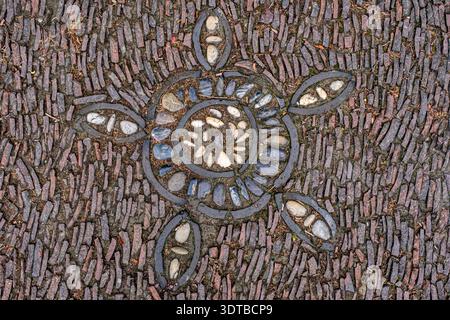 a cobblestone pavement featuring an intricate, symmetrical pattern with alternating dark and light stones forming a geometric design. Stock Photo