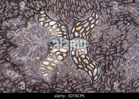 a cobblestone pavement featuring an intricate, symmetrical pattern with alternating dark and light stones forming a geometric design. Stock Photo