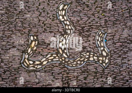 a cobblestone pavement featuring an intricate, symmetrical pattern with alternating dark and light stones forming a geometric design. Stock Photo