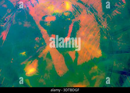 A vibrant, abstract artwork featuring a close-up of a shiny, surface reflecting multicolored light. The dominant hues are red, orange, yellow, and pin Stock Photo