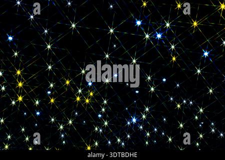 a starry night sky with a black background. Each star has a radiant, starburst pattern with multiple thin, colorful rays extending from the center. Stock Photo