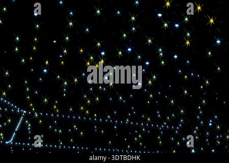 a starry night sky with a black background. Each star has a radiant, starburst pattern with multiple thin, colorful rays extending from the center. Stock Photo